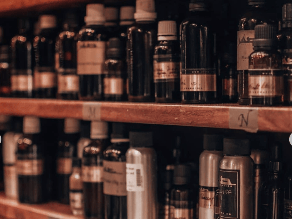 Close-up of a perfumer's organ with numerous ingredients in various sizes and bottles, all marked by hand and with gold labels.